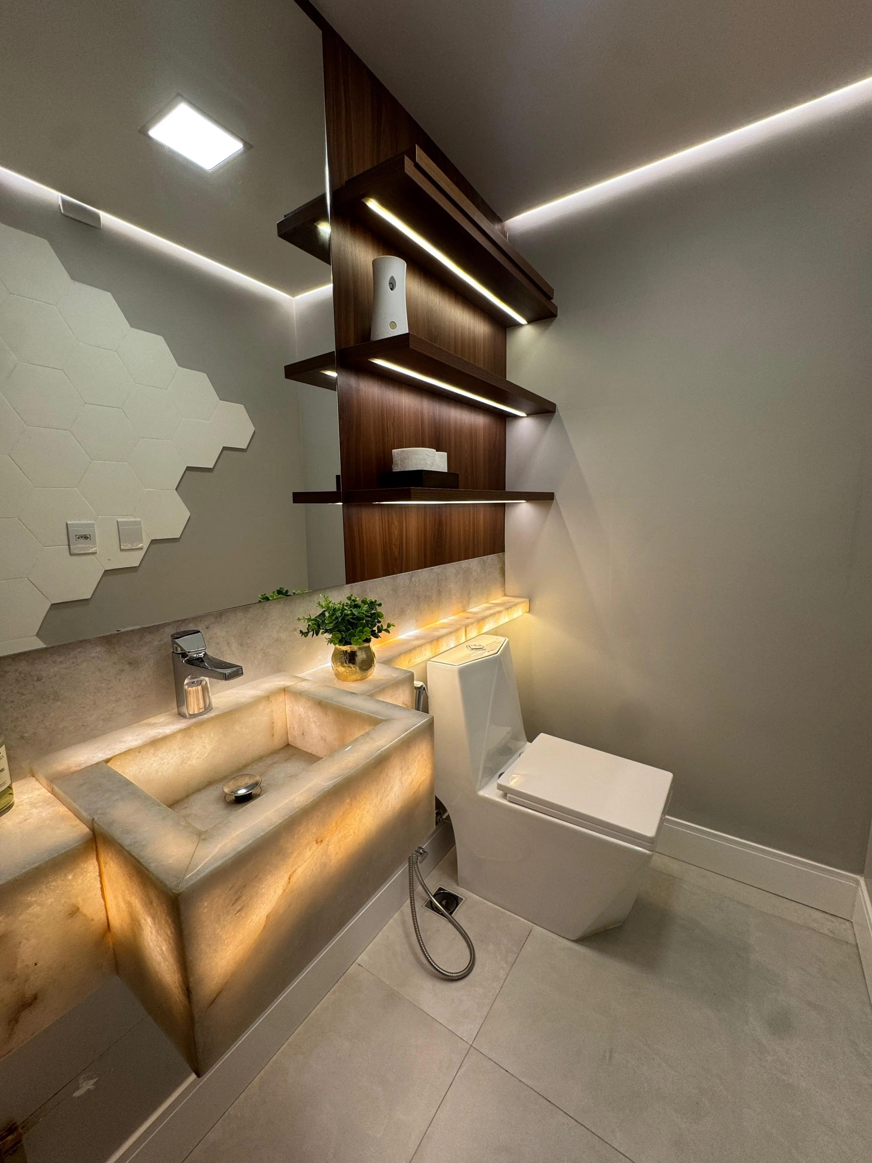 Lavabo com cuba em onix iluminada e revestimento hexagonal